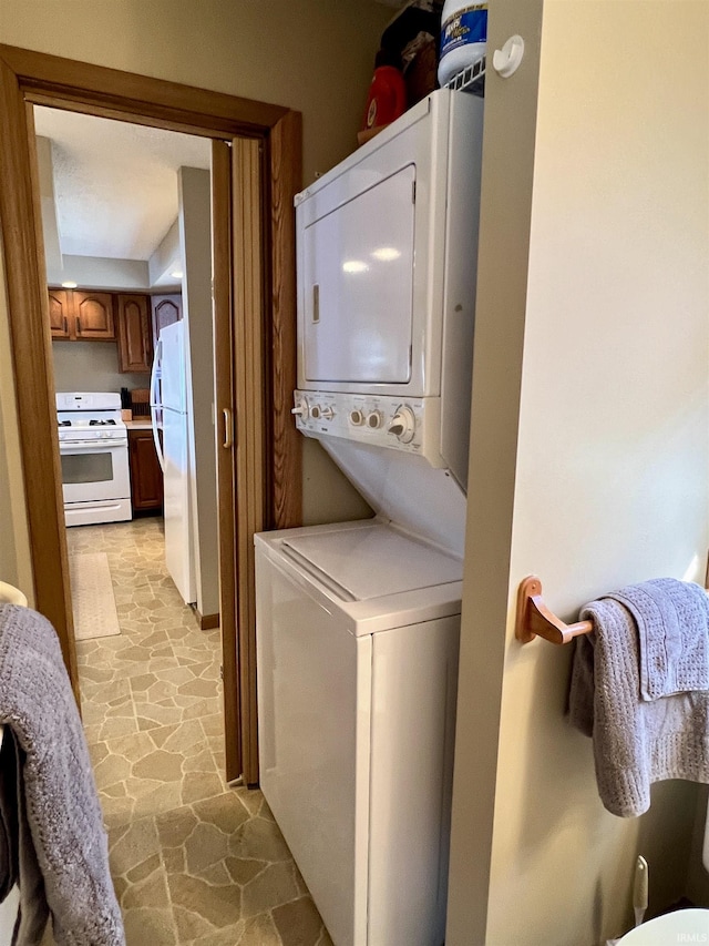 laundry room featuring stacked washer / dryer, stone finish floor, and laundry area