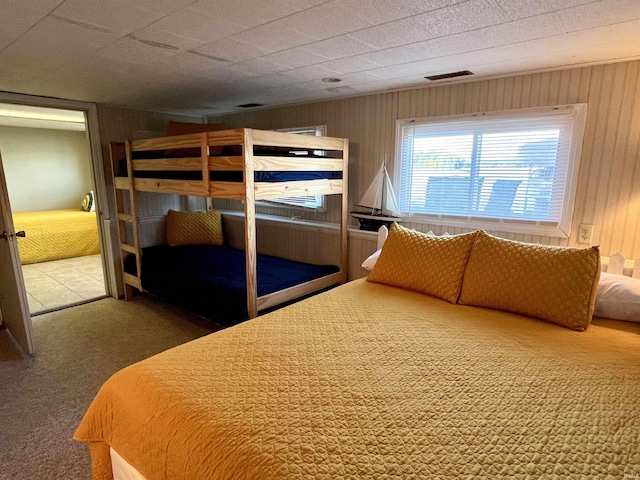 unfurnished bedroom with wood walls, carpet, and visible vents