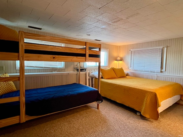 carpeted bedroom with wood walls