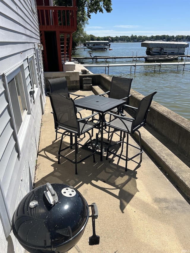 view of patio / terrace with outdoor dining space, a water view, and a boat dock