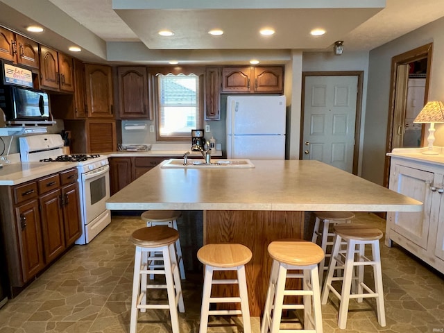 kitchen with white appliances, light countertops, stone finish flooring, and a sink