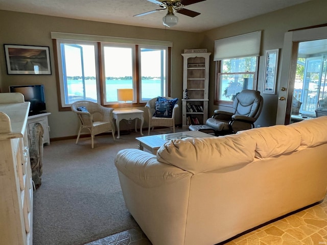 carpeted living room with a water view, ceiling fan, and a wealth of natural light