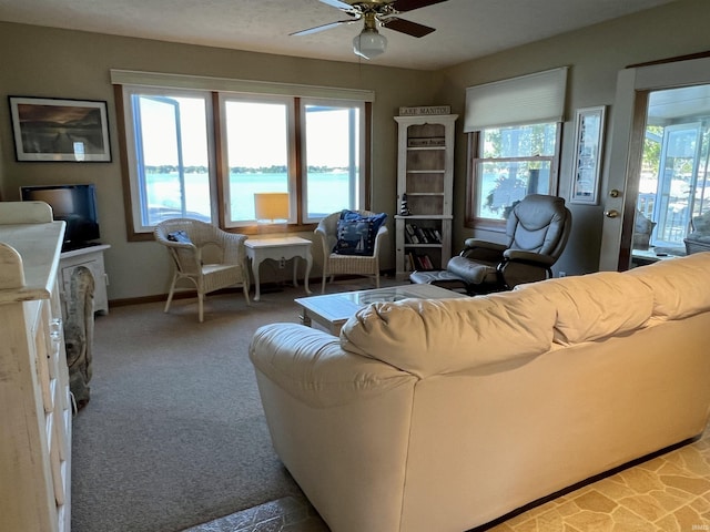 carpeted living area featuring a wealth of natural light, ceiling fan, and baseboards