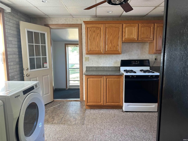 kitchen featuring ceiling fan, washer / clothes dryer, a drop ceiling, light carpet, and white range with gas cooktop