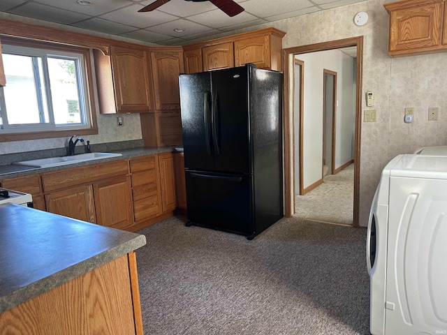 kitchen with ceiling fan, a paneled ceiling, washer / dryer, carpet floors, and black refrigerator