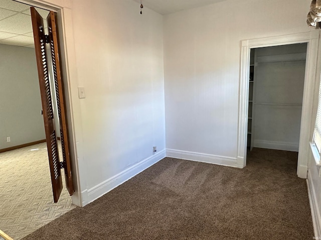 unfurnished bedroom featuring a drop ceiling and carpet floors