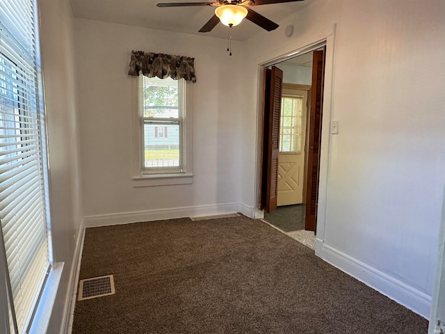 spare room with ceiling fan and dark carpet