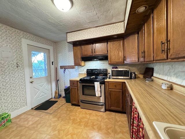 kitchen with a textured ceiling, appliances with stainless steel finishes, and light parquet floors