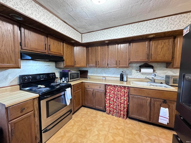 kitchen featuring sink, stainless steel appliances, tasteful backsplash, light parquet floors, and a textured ceiling