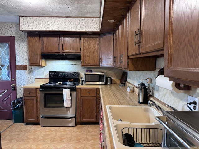 kitchen with decorative backsplash, appliances with stainless steel finishes, a textured ceiling, and sink