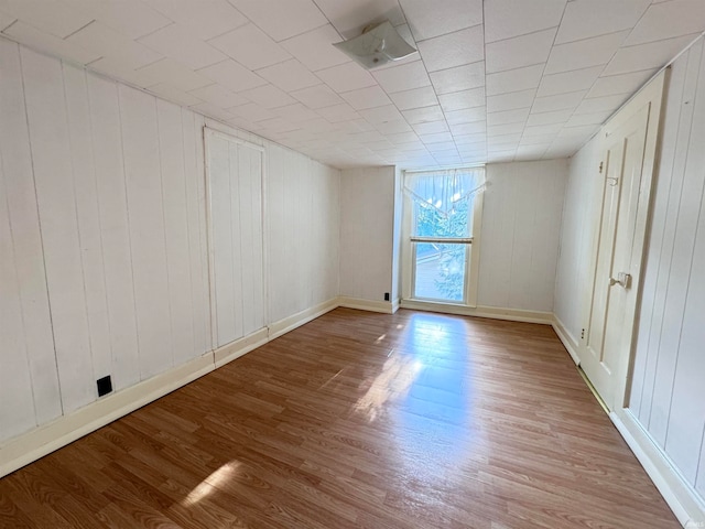 unfurnished room with wooden walls and light hardwood / wood-style flooring