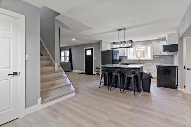 kitchen with a wealth of natural light, a center island, light hardwood / wood-style floors, and white cabinetry