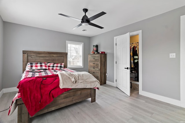 bedroom featuring light hardwood / wood-style flooring, ceiling fan, a spacious closet, and a closet