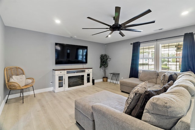 living room with light hardwood / wood-style flooring, ceiling fan, and a fireplace