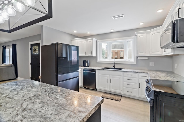 kitchen featuring white cabinetry, sink, light stone countertops, appliances with stainless steel finishes, and light hardwood / wood-style floors