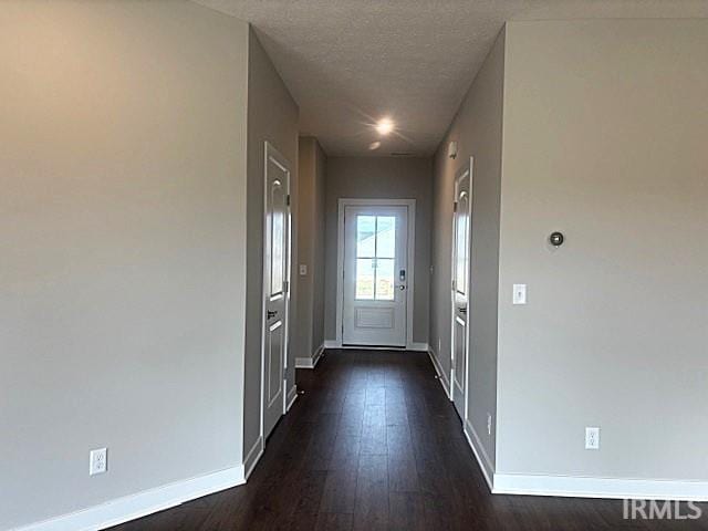 doorway to outside with a textured ceiling and dark wood-type flooring