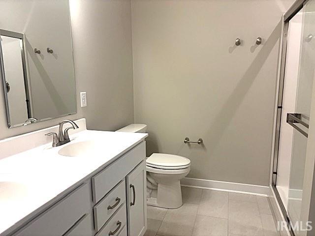 full bath with toilet, a stall shower, vanity, and tile patterned flooring