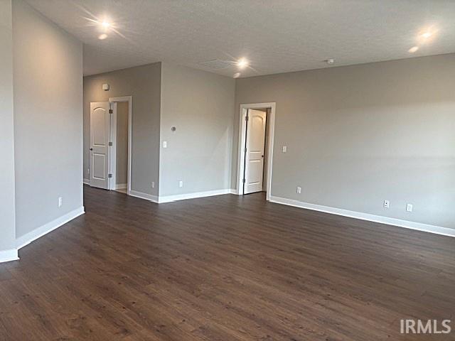 unfurnished room with a textured ceiling and dark hardwood / wood-style floors