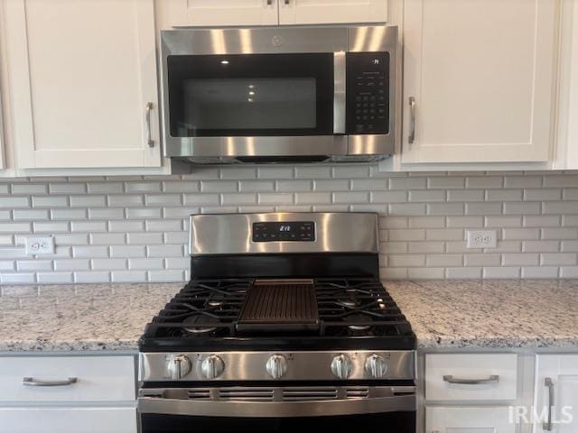 kitchen with white cabinetry, decorative backsplash, light stone counters, and stainless steel appliances