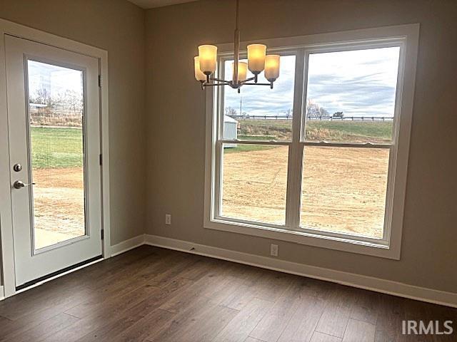 unfurnished dining area with dark hardwood / wood-style flooring and an inviting chandelier