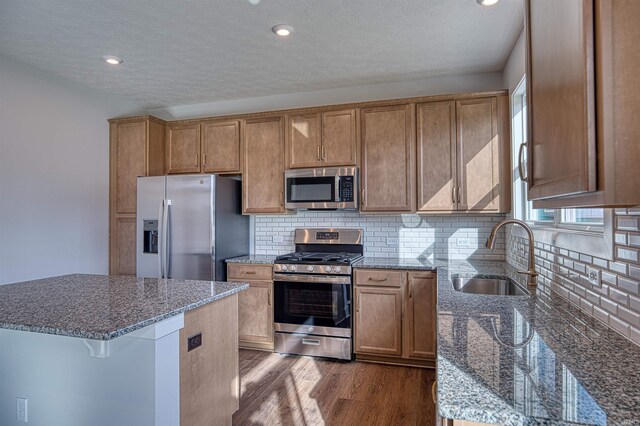 kitchen featuring stone counters, dark wood-type flooring, sink, decorative backsplash, and appliances with stainless steel finishes