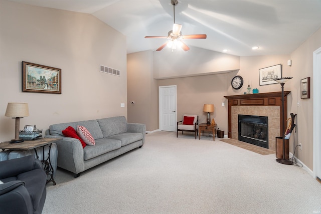 carpeted living room featuring lofted ceiling, ceiling fan, and a tiled fireplace