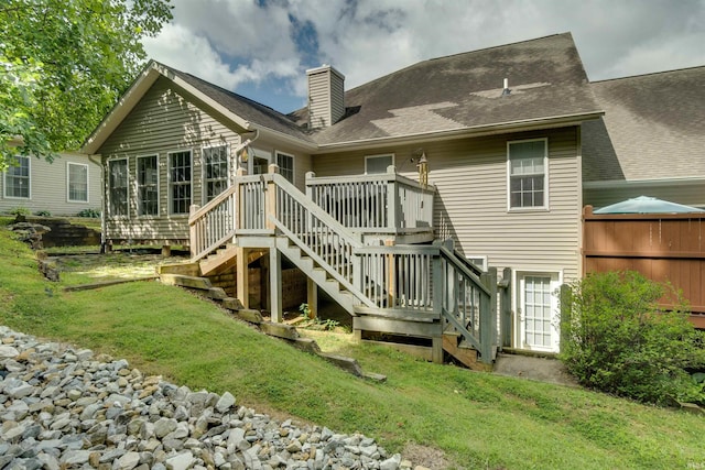 rear view of house featuring a deck and a lawn