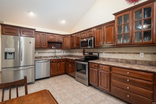 kitchen featuring stainless steel appliances, sink, lofted ceiling, light tile patterned flooring, and decorative backsplash