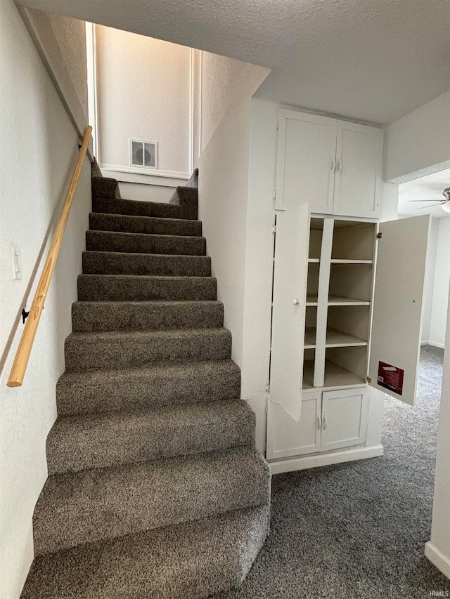 staircase with a textured ceiling and carpet