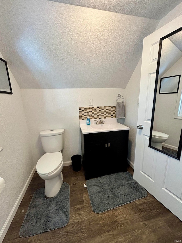 bathroom with lofted ceiling, hardwood / wood-style floors, toilet, and vanity