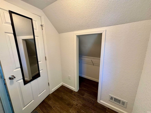 interior space with lofted ceiling, dark hardwood / wood-style floors, and a textured ceiling