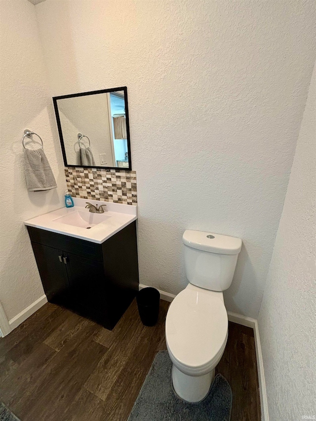 bathroom featuring hardwood / wood-style floors, backsplash, toilet, and vanity