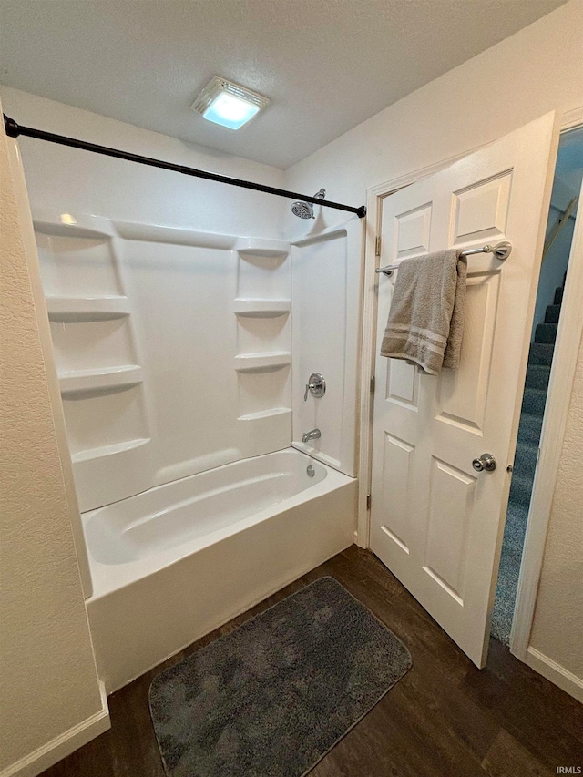 bathroom featuring a textured ceiling, wood-type flooring, and bathtub / shower combination