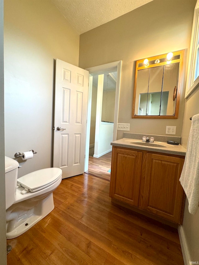 bathroom with hardwood / wood-style floors, vanity, toilet, and a textured ceiling