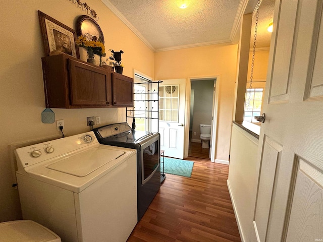 clothes washing area with cabinets, ornamental molding, a textured ceiling, washing machine and clothes dryer, and dark wood-type flooring