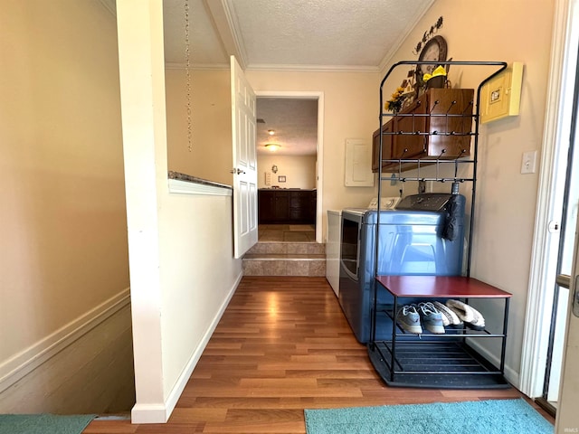 corridor featuring a textured ceiling, crown molding, hardwood / wood-style floors, and independent washer and dryer