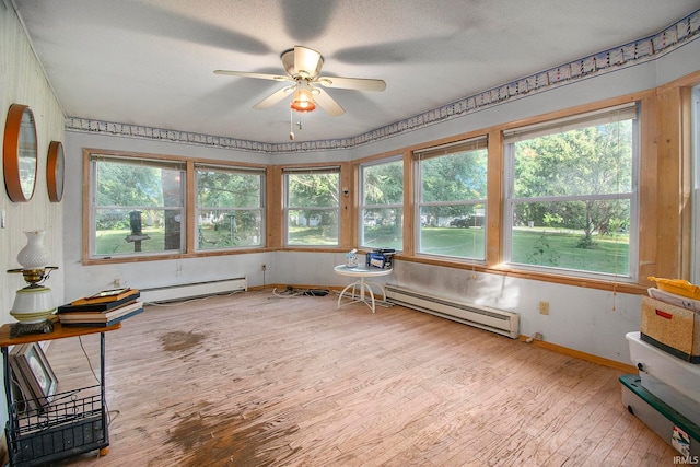 unfurnished sunroom featuring a baseboard radiator and ceiling fan