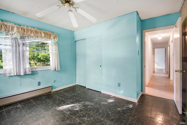 unfurnished bedroom with baseboard heating, ceiling fan, a closet, and dark hardwood / wood-style flooring