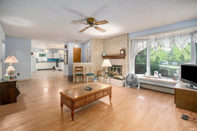 living room with light wood-type flooring, plenty of natural light, a fireplace, and ceiling fan