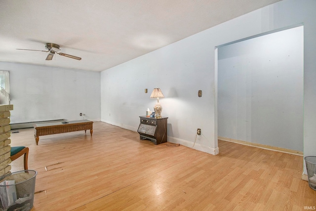 living area with a baseboard heating unit, ceiling fan, a stone fireplace, and light hardwood / wood-style floors