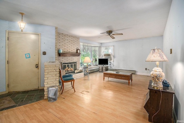 living room featuring ceiling fan, a fireplace, and light hardwood / wood-style floors