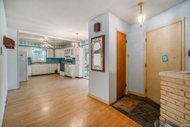 foyer with ceiling fan with notable chandelier, a textured ceiling, and light hardwood / wood-style flooring