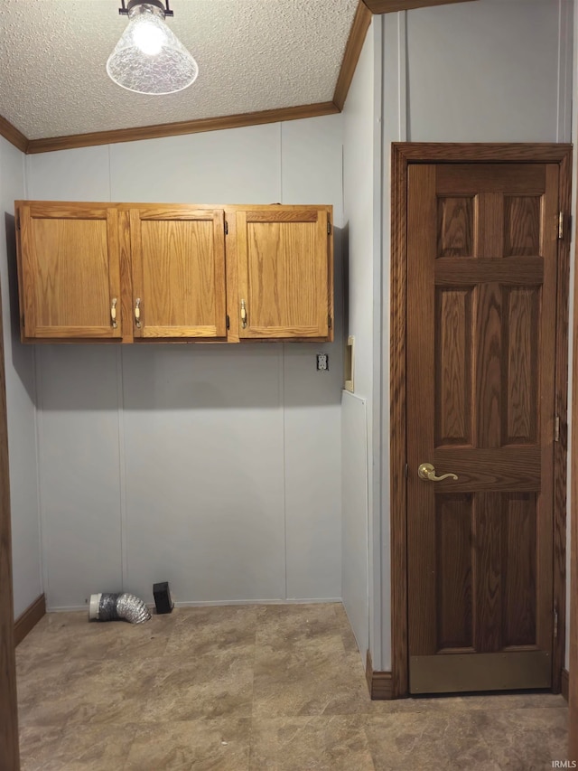 laundry area with ornamental molding, cabinets, and a textured ceiling