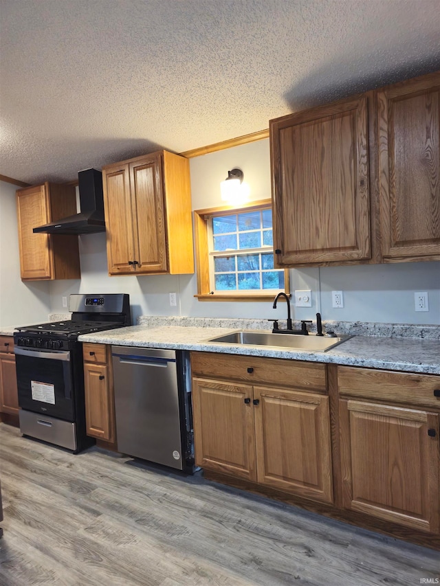 kitchen featuring wall chimney range hood, stainless steel appliances, a textured ceiling, and sink