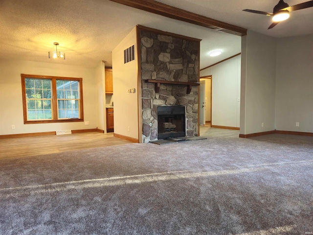 unfurnished living room with a textured ceiling, a fireplace, lofted ceiling, light colored carpet, and ceiling fan