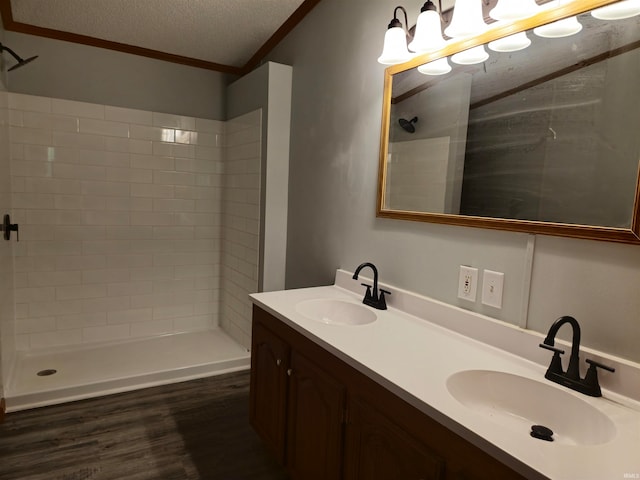 bathroom featuring crown molding, a textured ceiling, a tile shower, wood-type flooring, and vanity