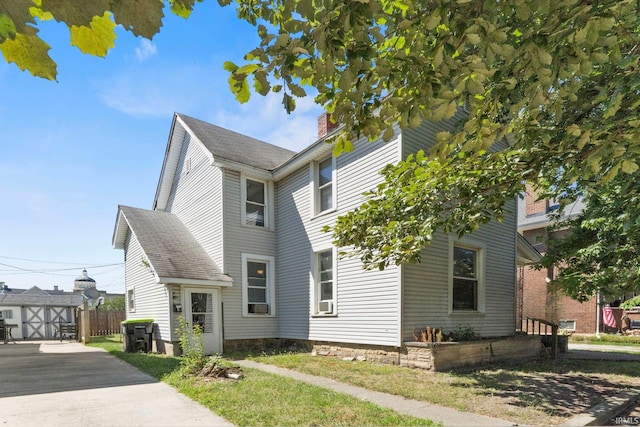 view of front of property featuring a storage shed