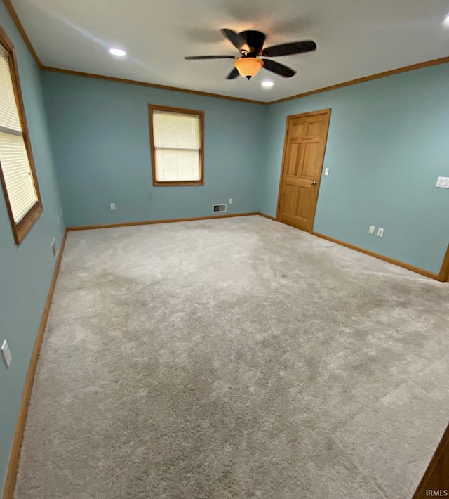 empty room with carpet flooring, ceiling fan, and ornamental molding