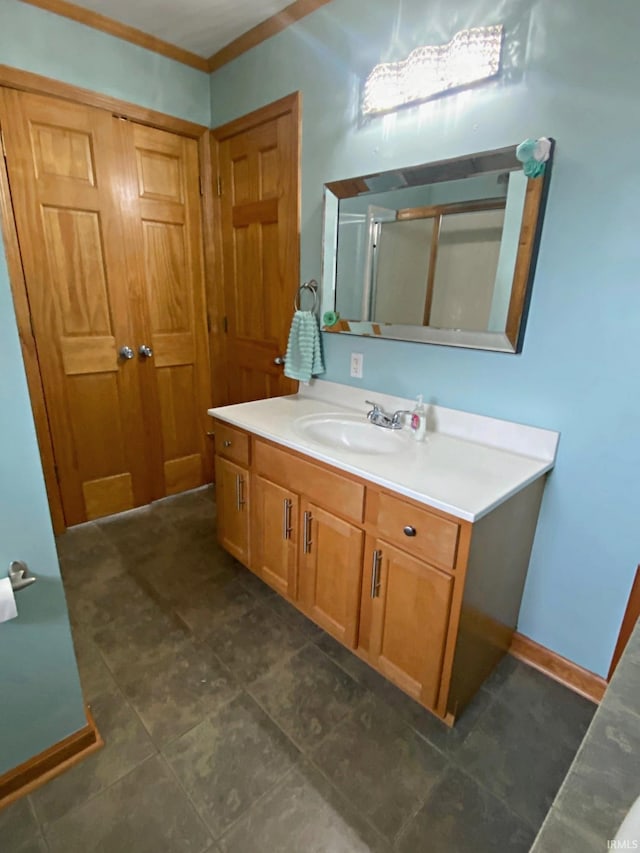 bathroom featuring ornamental molding, vanity, and a shower with shower door