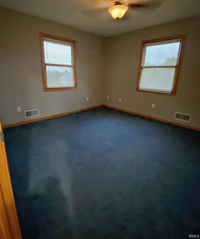 carpeted spare room featuring plenty of natural light and ceiling fan